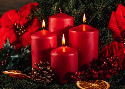 Three burning Red advent candles in advent wreath decoration on wooden dark background.