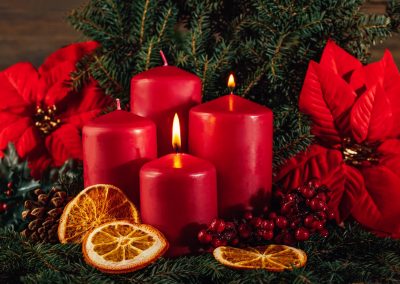 Two burning Red advent candles in advent wreath decoration on wooden dark background